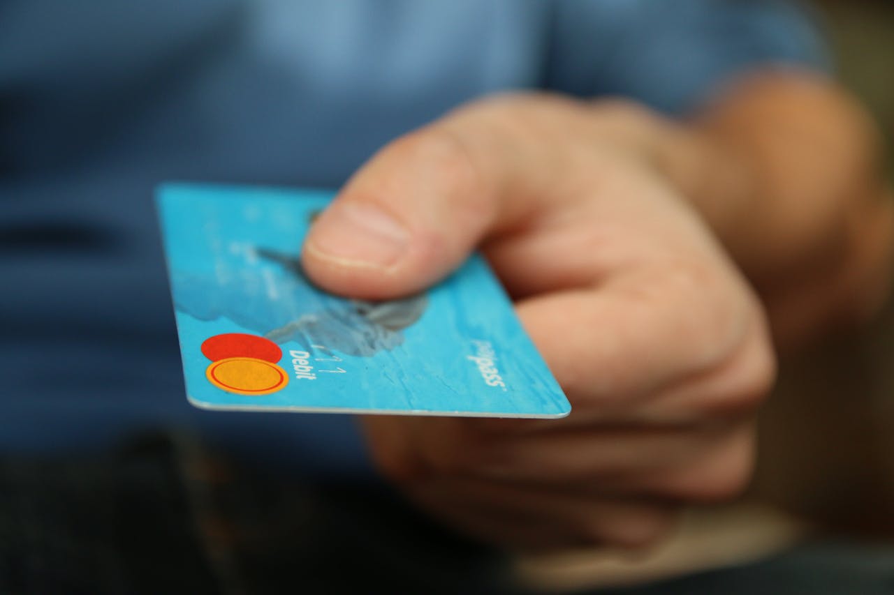ours-journey A close-up shot of a hand offering a blue debit card for payment.